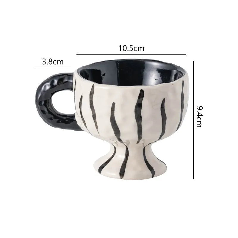 Hand-pinched irregularly shaped ceramic mug in a solid colour, shown on a table.
