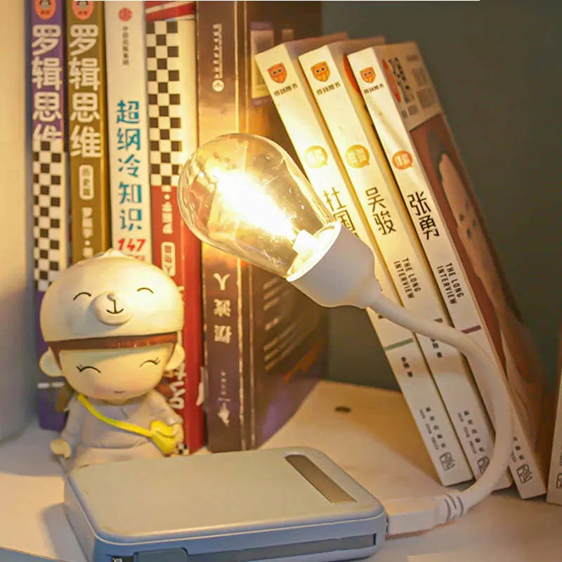 USB rechargeable folding night light with a glowing tungsten filament bulb on a table.