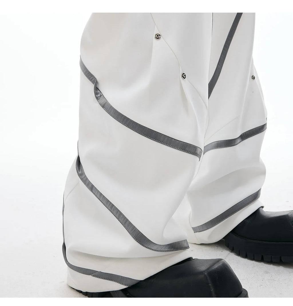 Men's black trousers with three-dimensional cut and silver metal rivet pleat detailing.