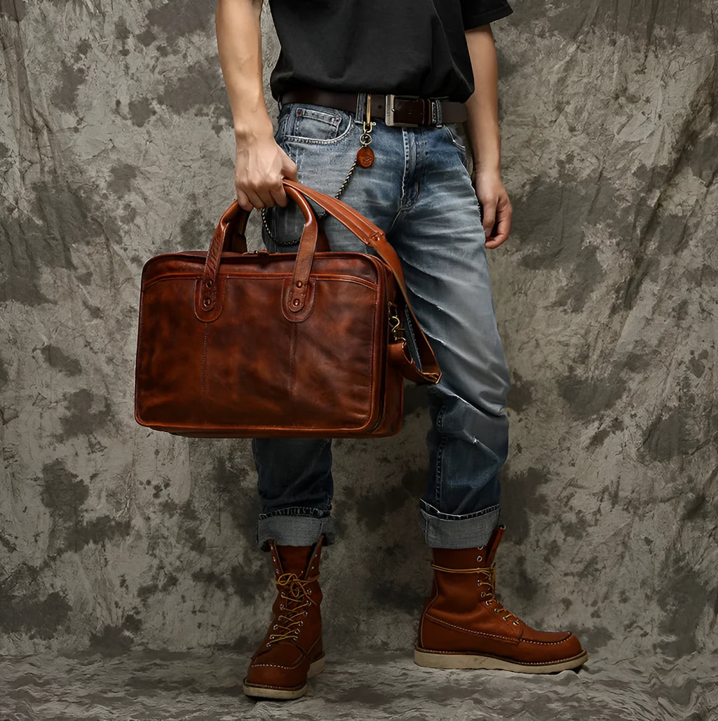 Black vintage leather men's briefcase open to show internal laptop pocket, camera pocket, and document organisation.