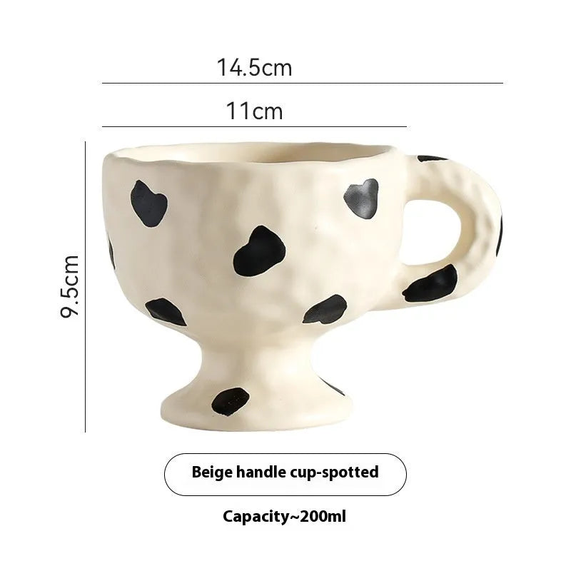 Hand-pinched irregularly shaped ceramic mug in a solid colour, shown on a table.