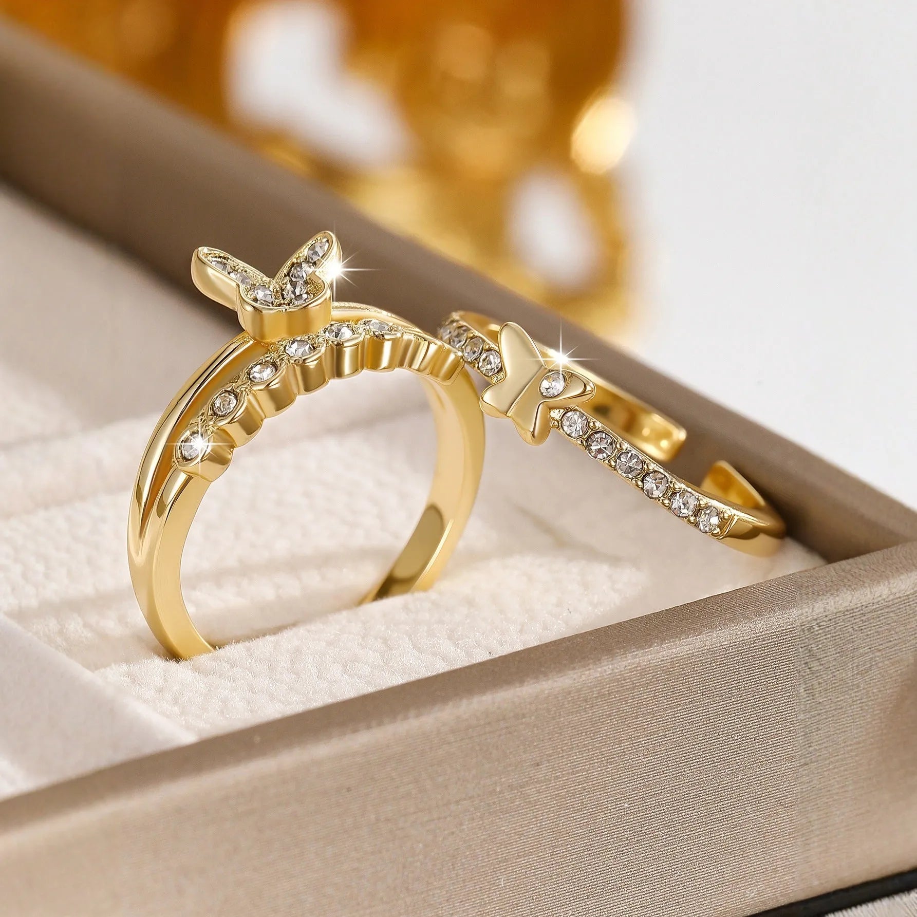 Gold adjustable butterfly ring on finger against white background