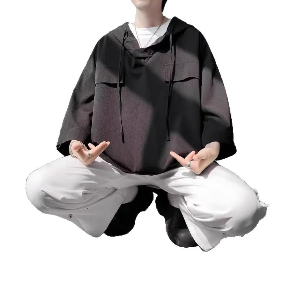 A man wearing a loose-fit black hooded short sleeve t-shirt made of polyester for summer.