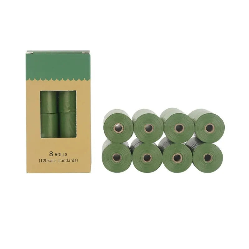 Roll of green EPI degradable dog poo bags next to a white plastic dispenser on a grass background.