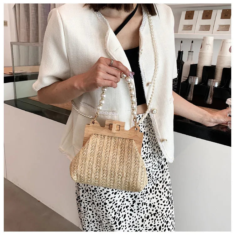 Women's woven straw shoulder bag with pearl chain strap in horizontal square shape showing sandwich pocket detail.