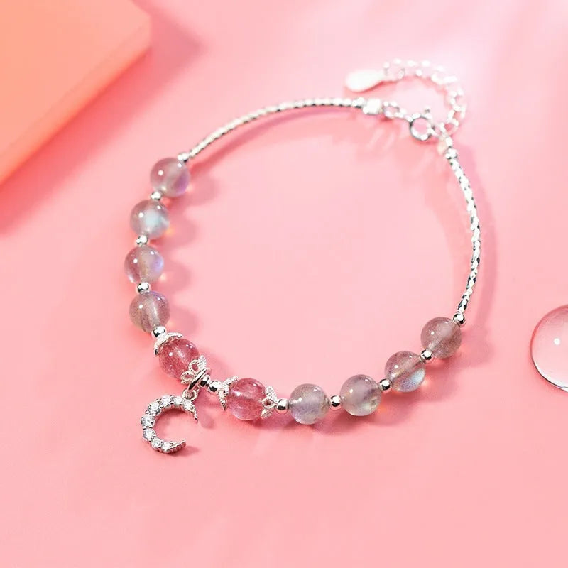 Handmade adjustable moonstone bracelet with crescent moon charm and crystal bead on a white background.