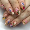 Almond-shaped false nails with detailed 3D pink rose and tulip floral designs on a solid colour base.