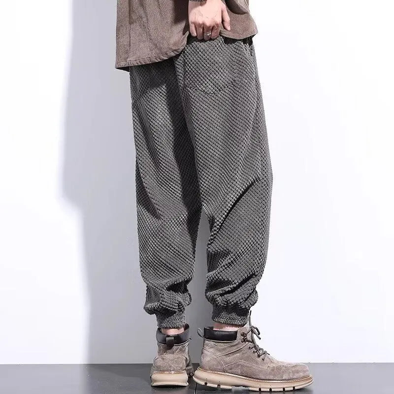 Men's grey ankle-tied straight leg sweatpants laid flat on a surface.