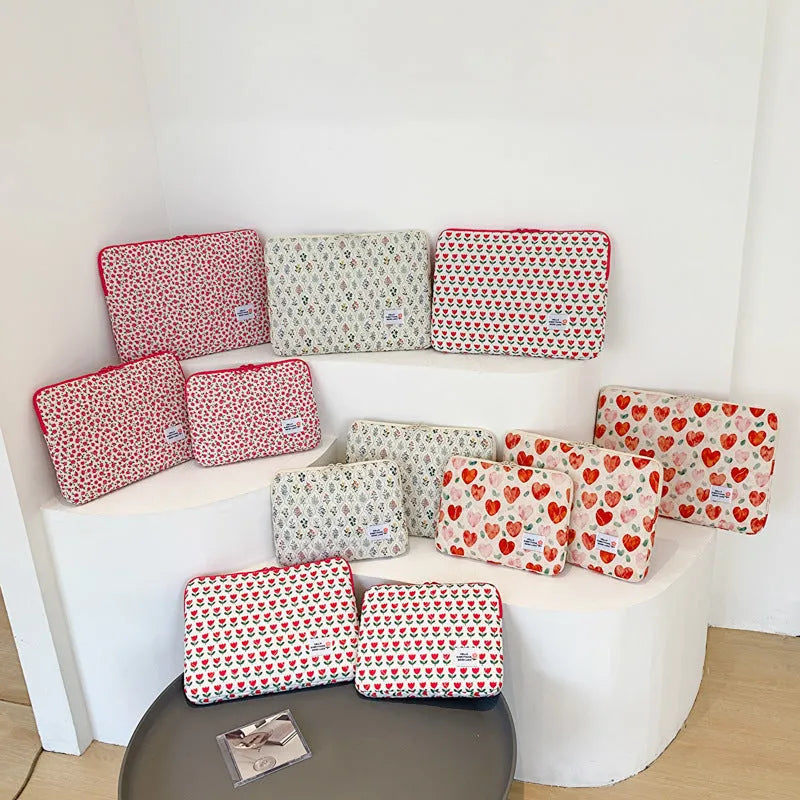 Floral print cloth laptop bag in green flower, pink floral, red flower, and red heart designs, showing three size options.