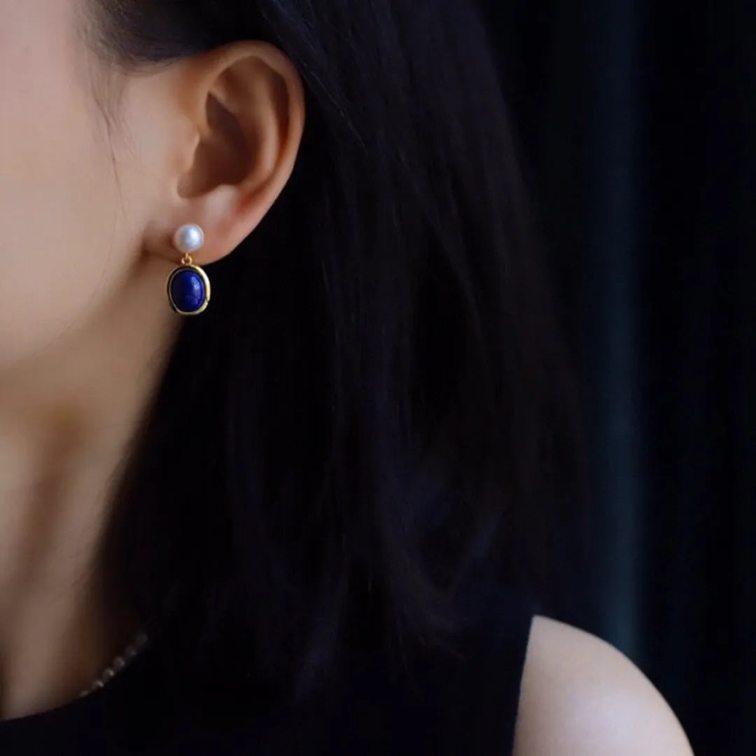 A pair of simple sterling silver drop earrings with a blue lapis lazuli pearl and auspicious patterns.