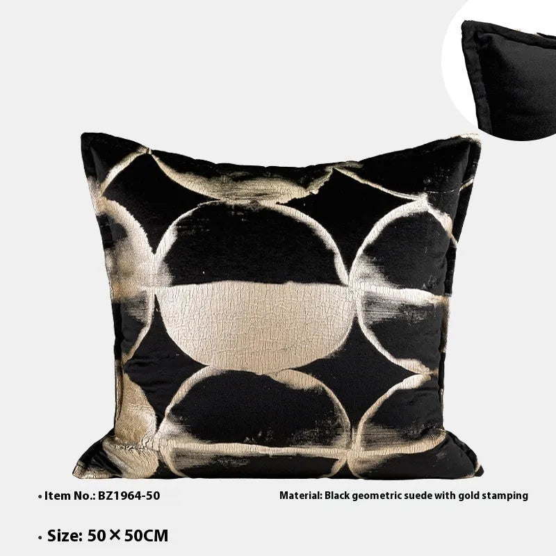 Black and gold abstract pattern decorative velvet cushion on a grey sofa.
