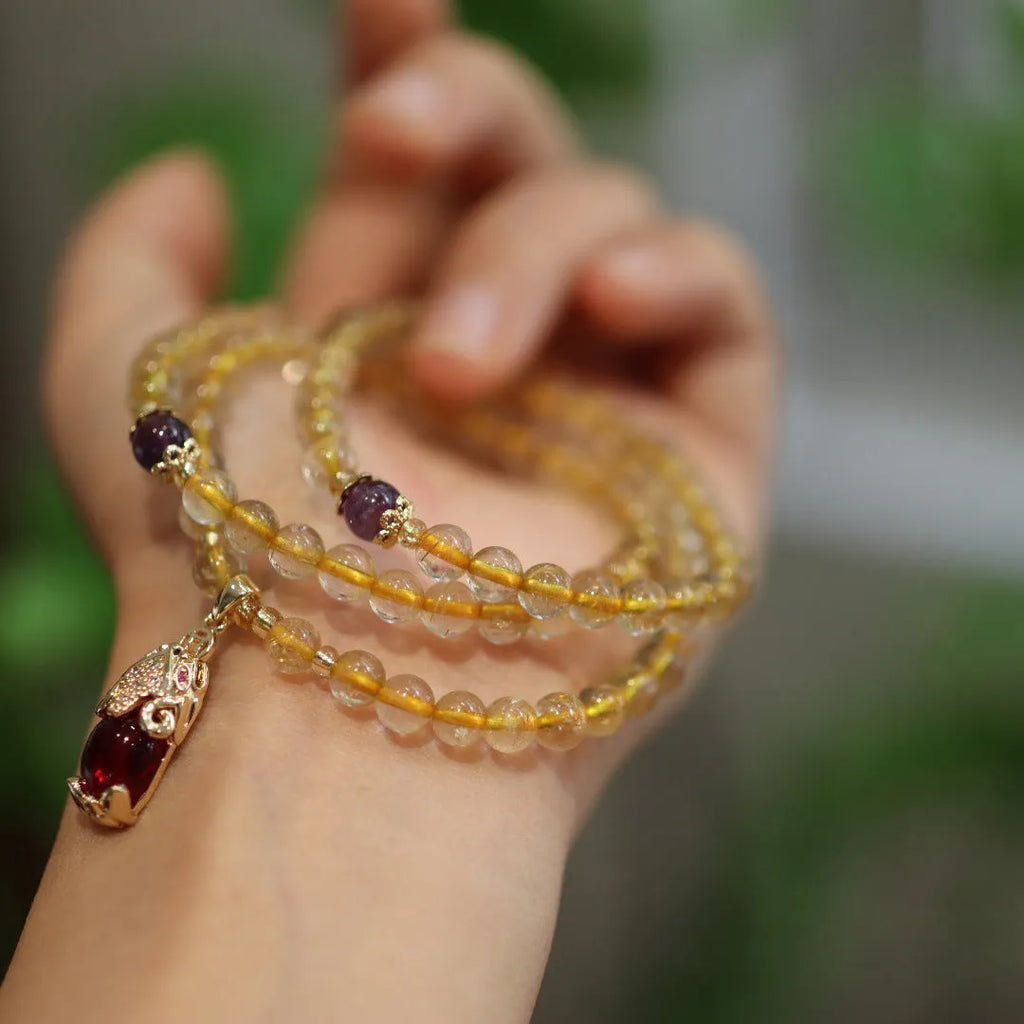 Handmade gold and ruby quartz Chinese bracelet with three circles and hanging chopstick detailing