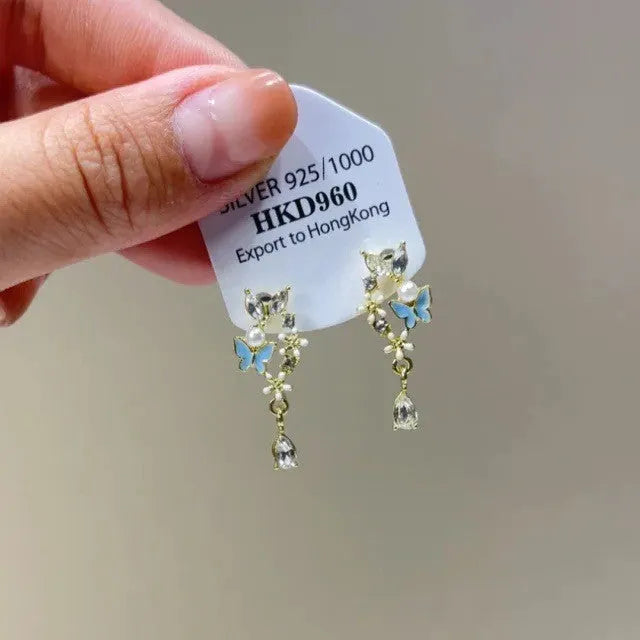 Geometric heart-shaped women's earrings with rhinestones and a silver tassel, shown on a white background.