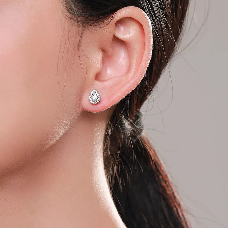 A pair of silver water drop shaped stud earrings with a diamond-cut faceted surface.