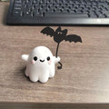Small resin statue of a ghost walking a dog and holding a bat, a mini Halloween ornament.