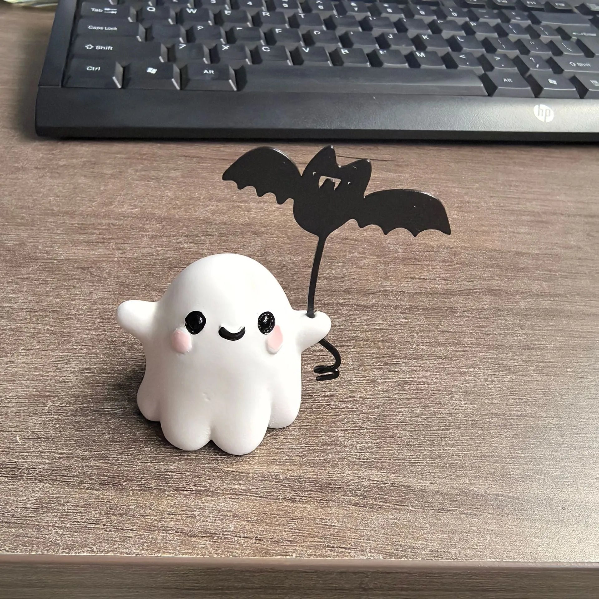Small resin statue of a ghost walking a dog and holding a bat, a mini Halloween ornament.