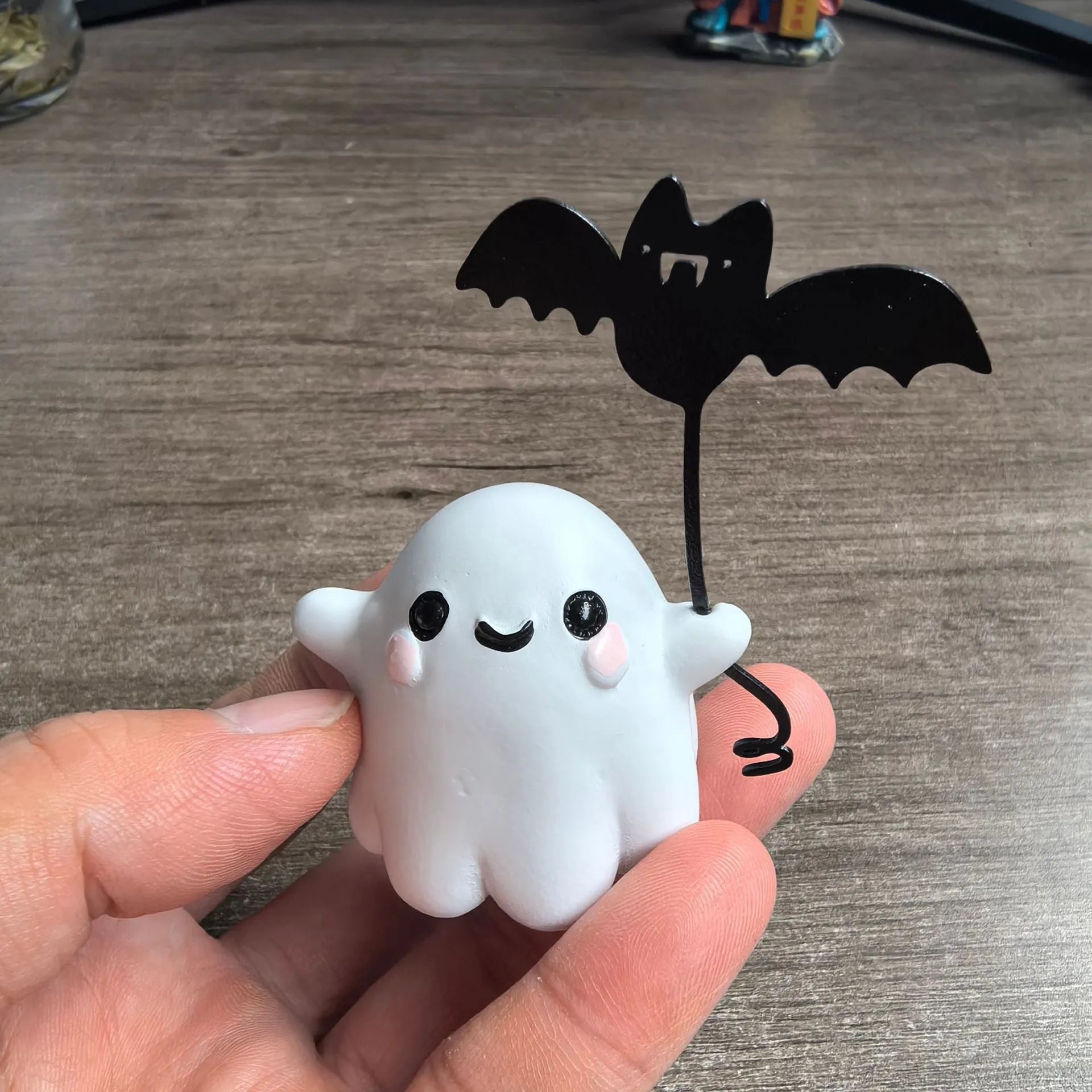 Small resin statue of a ghost walking a dog and holding a bat, a mini Halloween ornament.