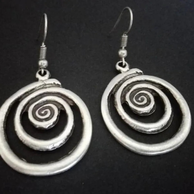 Geometric spiral distressed silver alloy drop earrings on a white background.