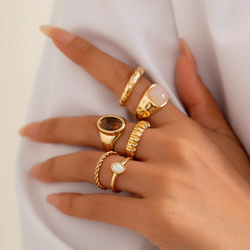 Six light gold alloy rings with geometric shapes and round elements arranged as a complete ring suit