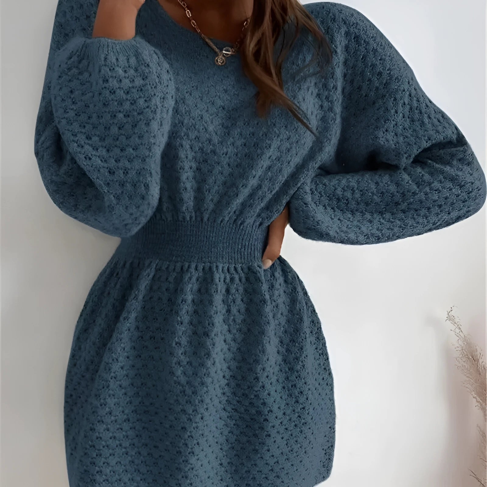 Blue women's knitted dress with hand-crocheted white flowers, a fitted waist, and a round neck.