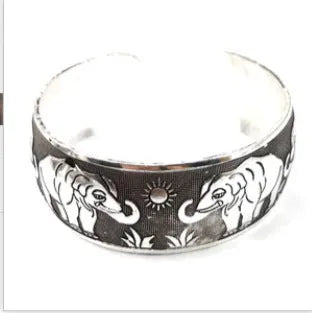 Ethnic style open carved Miao silver alloy bracelet in Roman shape on wrist.