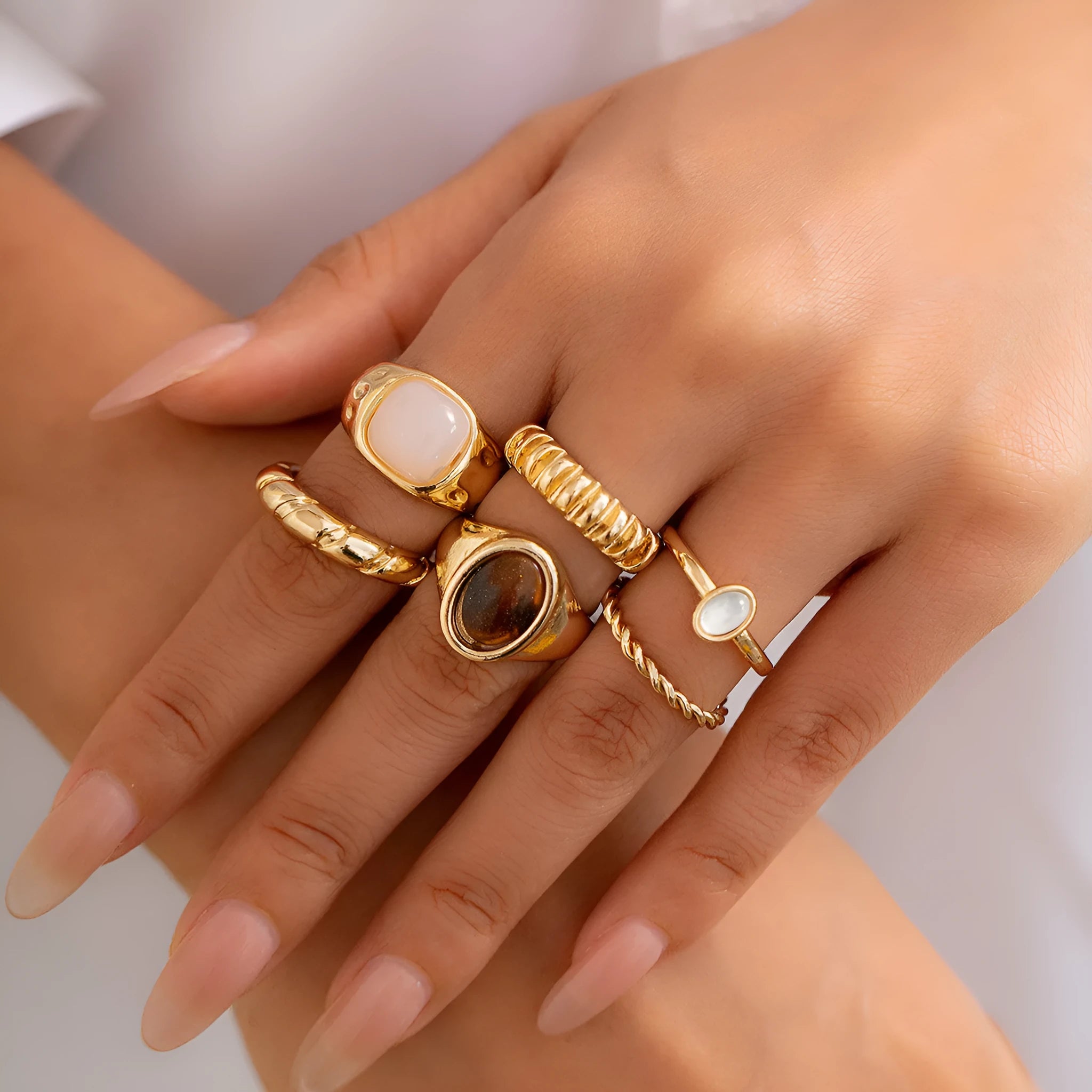 Six light gold alloy rings with geometric shapes and round elements arranged as a complete ring suit