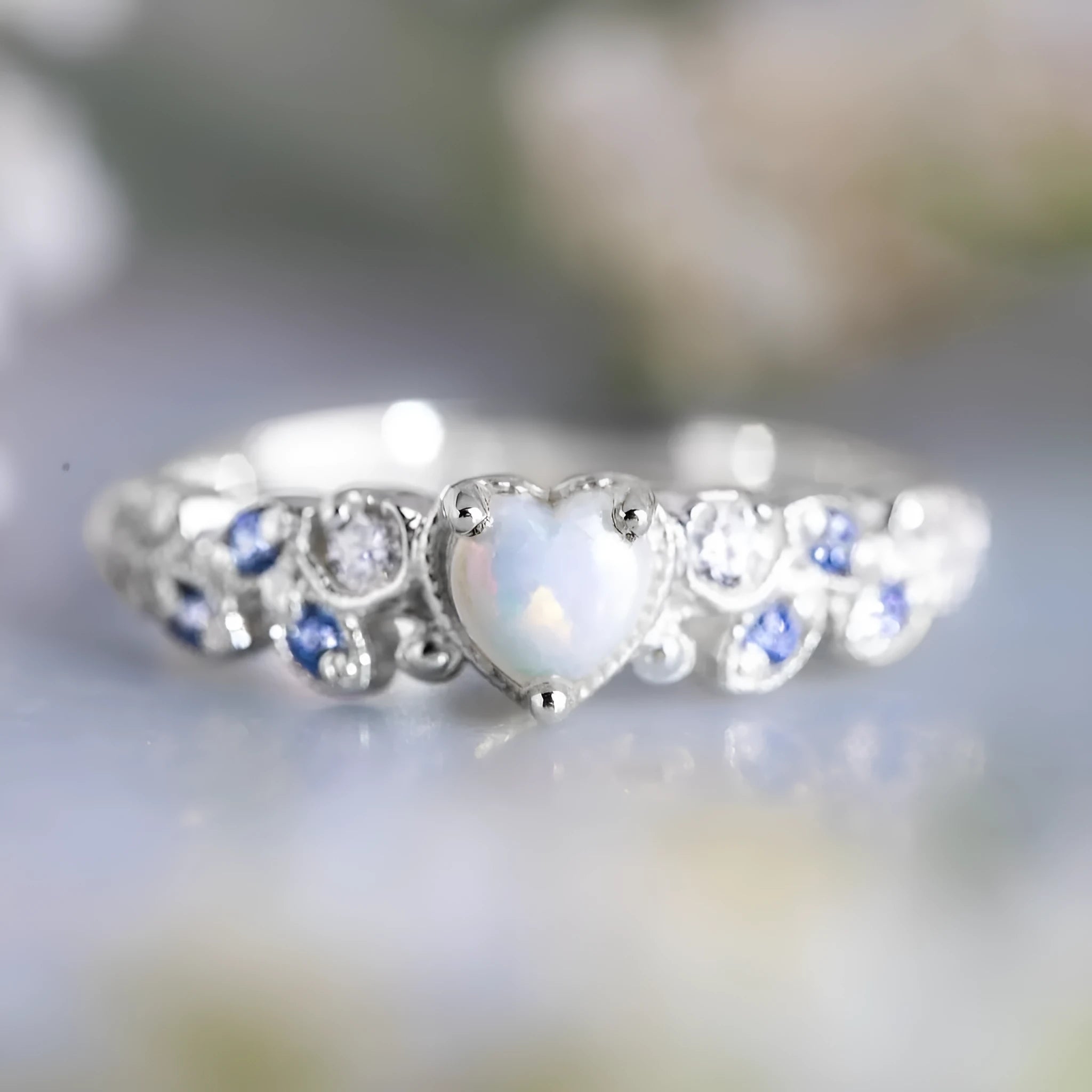 White electroplated alloy heart ring with floral opal ocean design on a jewellery display