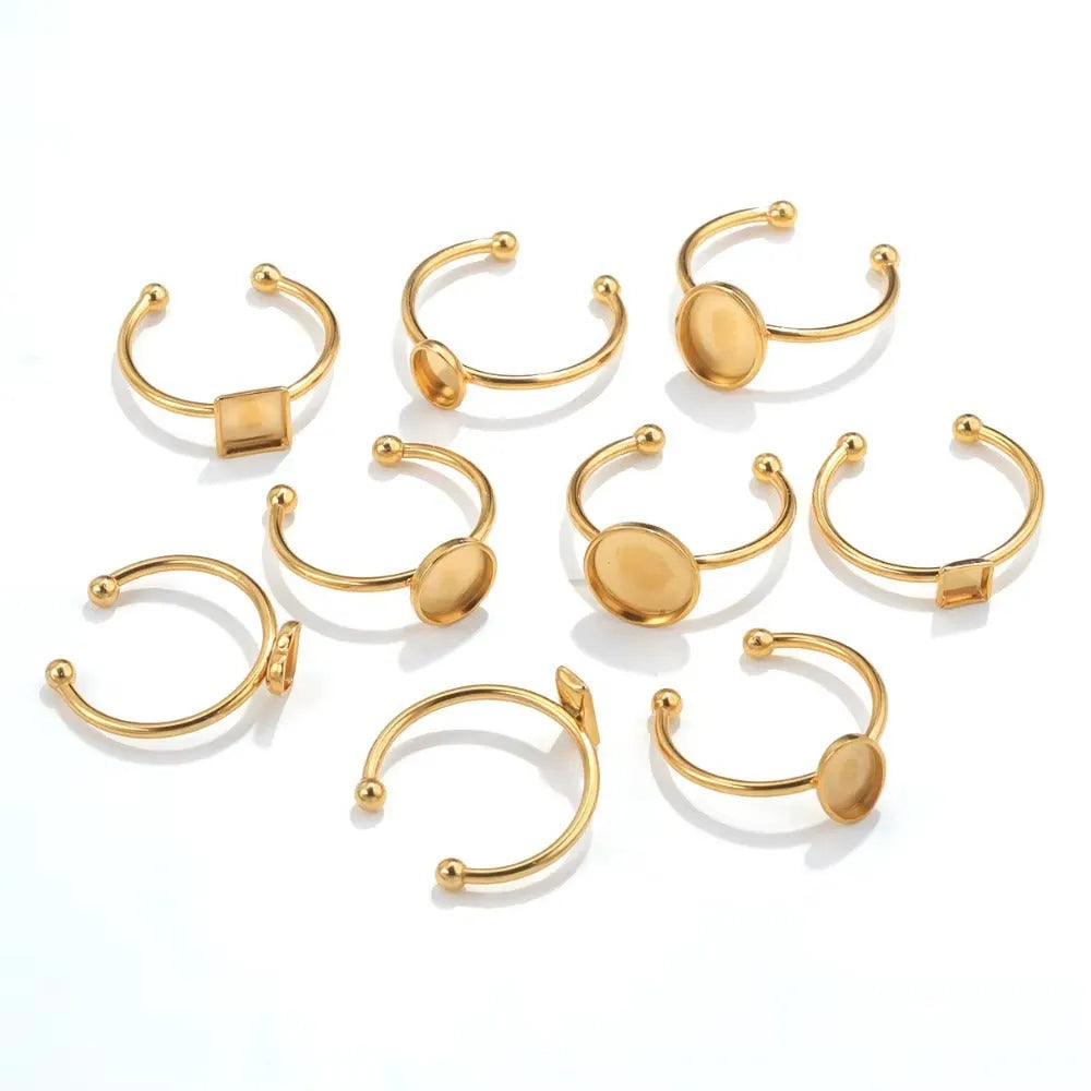 Assortment of golden stainless steel DIY jewellery settings in oval, heart, round, square, and rectangle shapes with totem pattern.