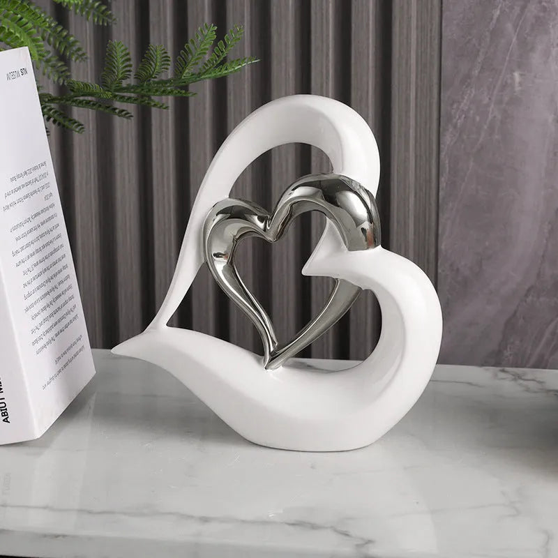 Modern white porcelain heart ornament in a metallic finish, showing its geometric shape on a table.
