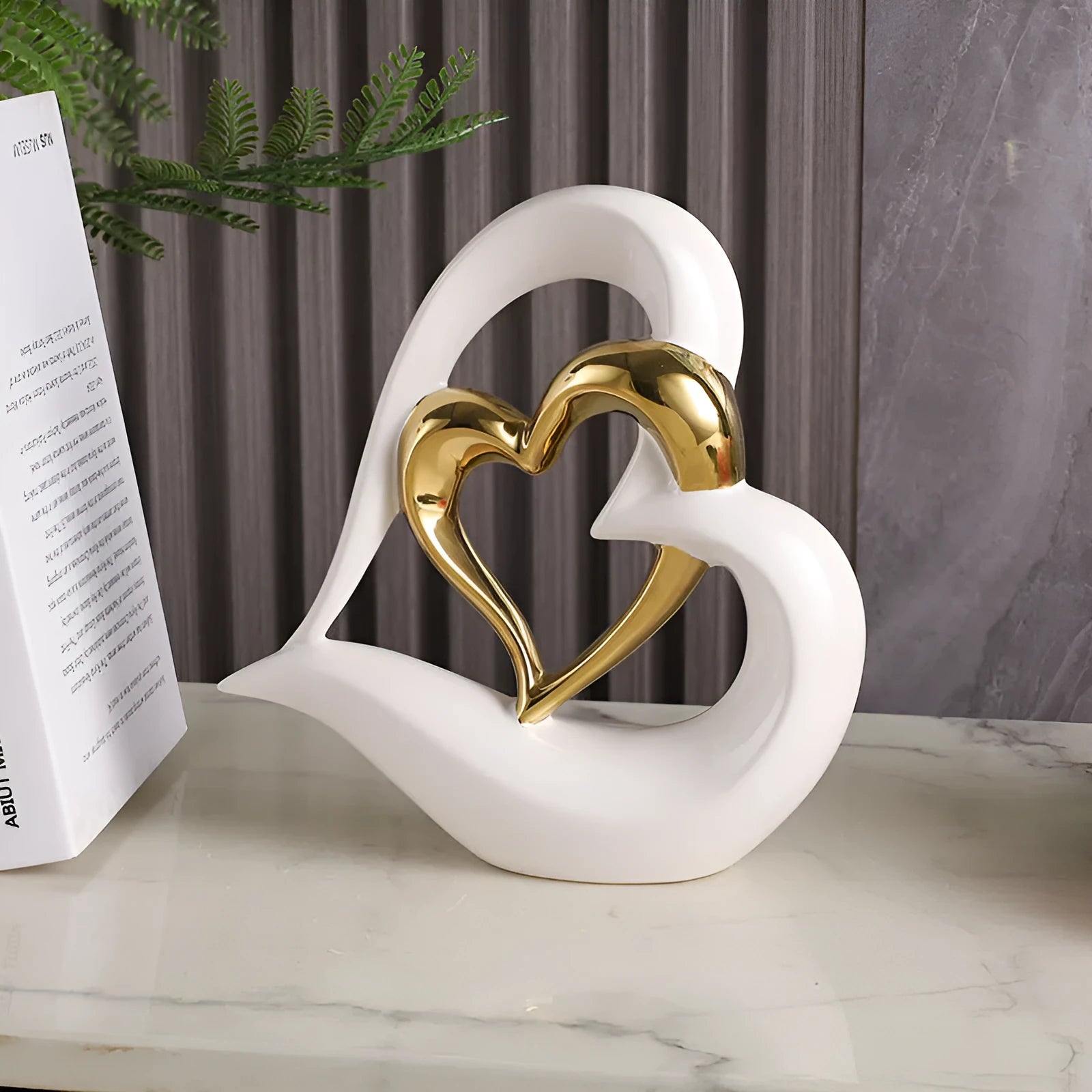 Modern white porcelain heart ornament in a metallic finish, showing its geometric shape on a table.
