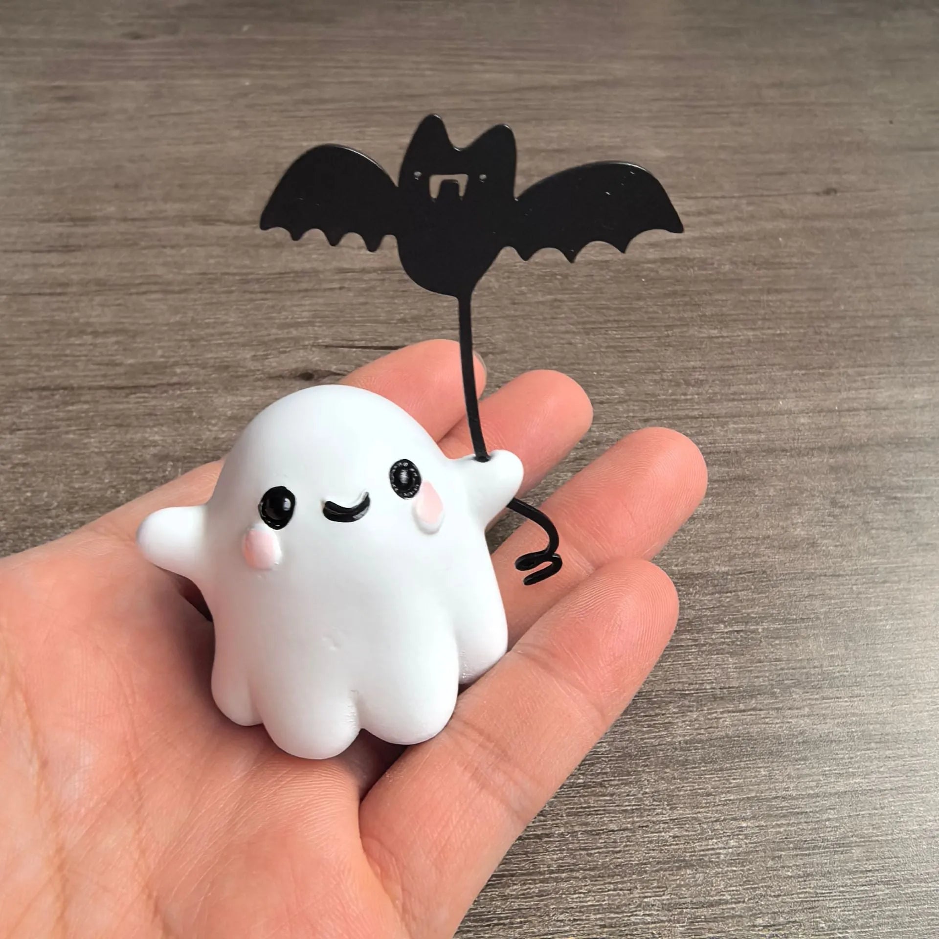 Small resin statue of a ghost walking a dog and holding a bat, a mini Halloween ornament.