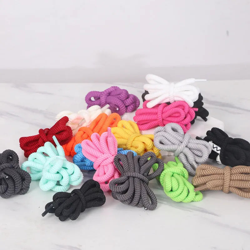 Oval cross-section shoelace adapter rope in various colours, shown next to a trainer and sweatshirt.