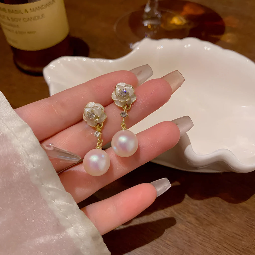 Close-up of Camellia Pearl Flower Stud Earrings for women, showing detailed floral alloy design with faux pearl centre.