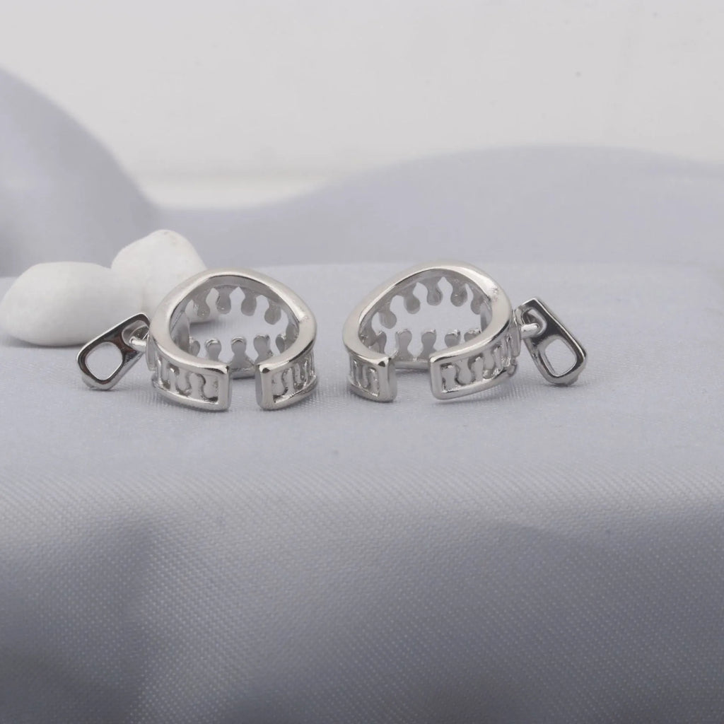 A pair of simple geometric copper clip-on earrings with a linear design on a white background.