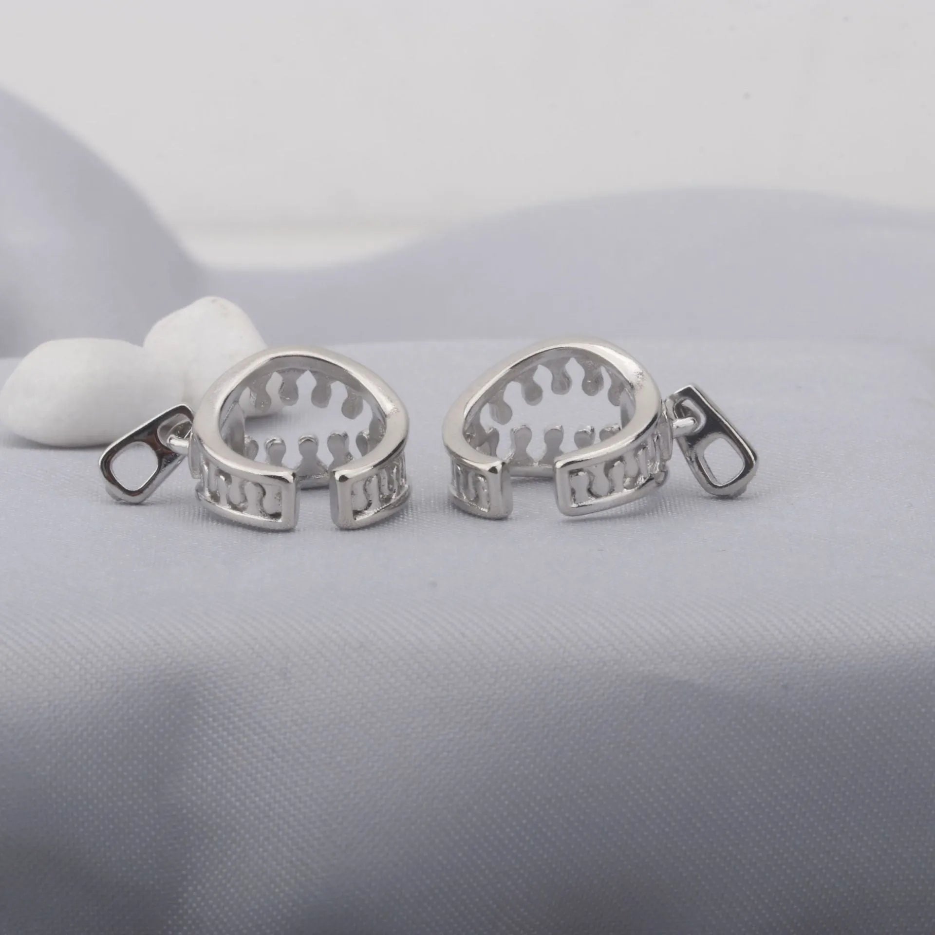 A pair of simple geometric copper clip-on earrings with a linear design on a white background.