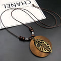 Wooden leaf pendant necklace with wax-line chain on a neutral background.