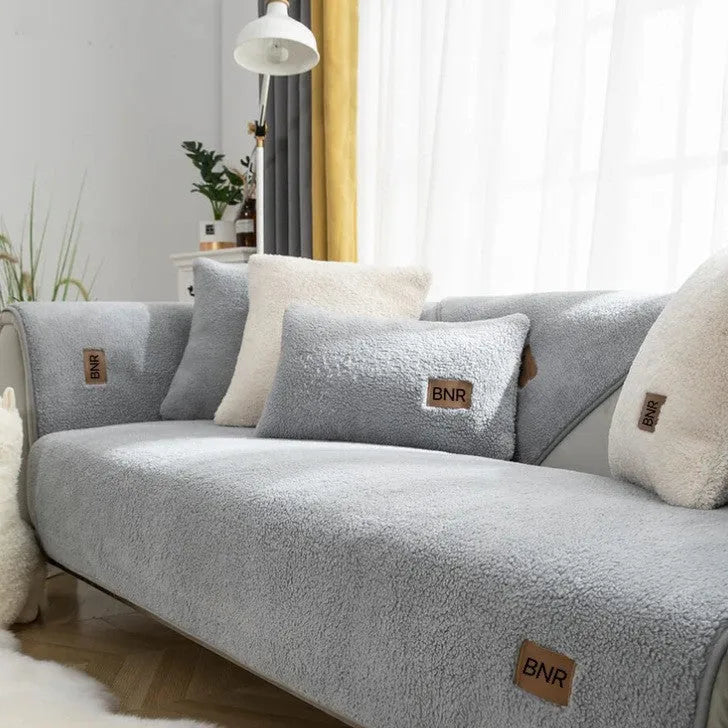 Lambswool solid colour sofa cover in blue on a grey sofa