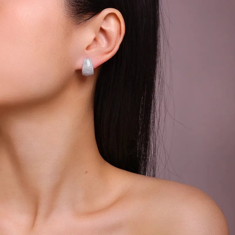 Geometric S925 sterling silver stud earrings with white moissanite stones on a gift box.