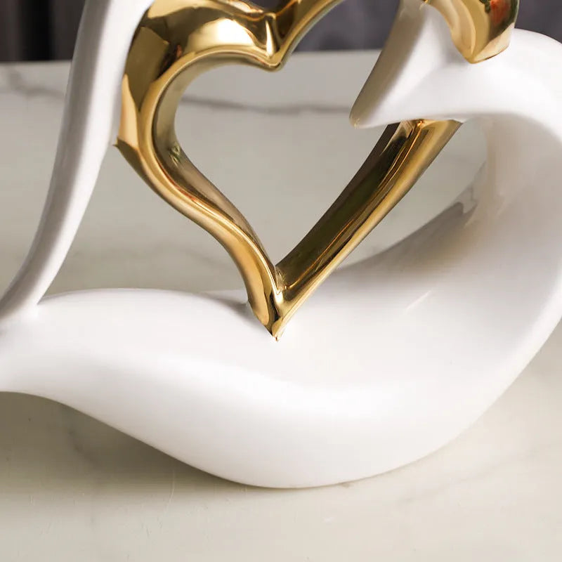 Modern white porcelain heart ornament in a metallic finish, showing its geometric shape on a table.
