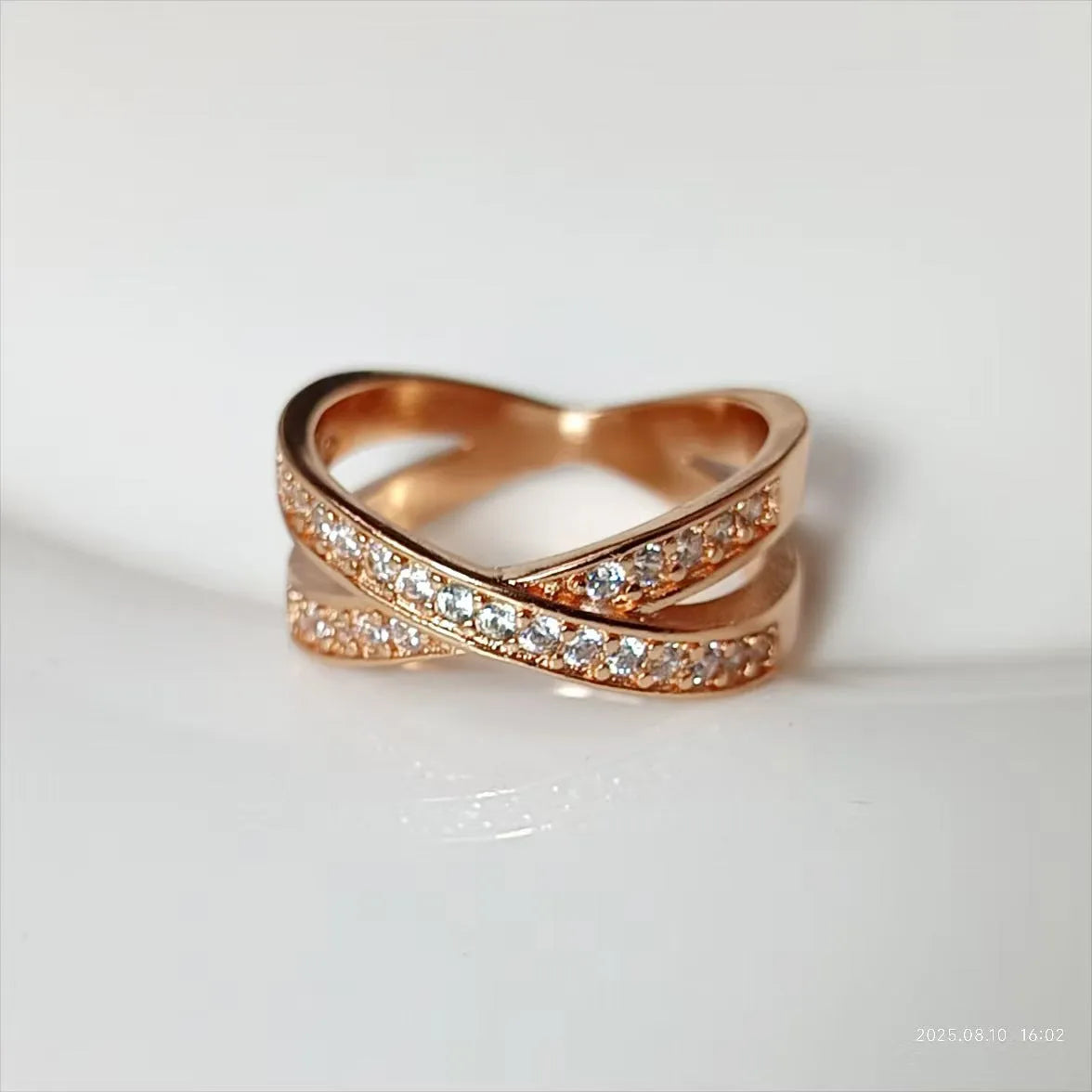 Simple metal cross ring with micro-inlaid zircon on a geometric band, shown in silver and rose gold finishes.
