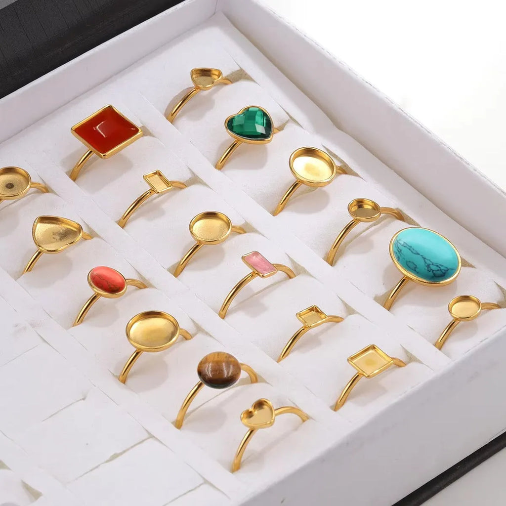 Assortment of golden stainless steel DIY jewellery settings in oval, heart, round, square, and rectangle shapes with totem pattern.