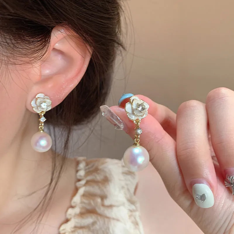 Close-up of Camellia Pearl Flower Stud Earrings for women, showing detailed floral alloy design with faux pearl centre.