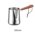 Stainless steel latte art milk cup with wooden handle and visible internal measurement scale.