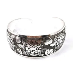 Ethnic style open carved Miao silver alloy bracelet in Roman shape on wrist.