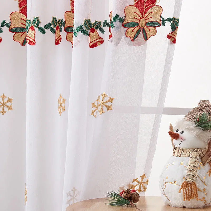 Pair of white Christmas curtains with detailed embroidered red and green snowflake design, showing texture and semi-sunshade fabric.
