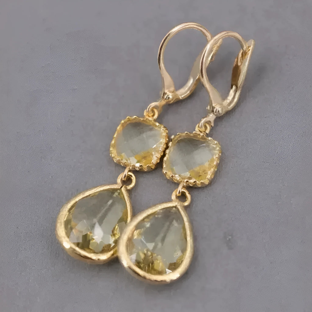 Gold long drop earrings with geometric shape and water droplet crystal fringe on a model.