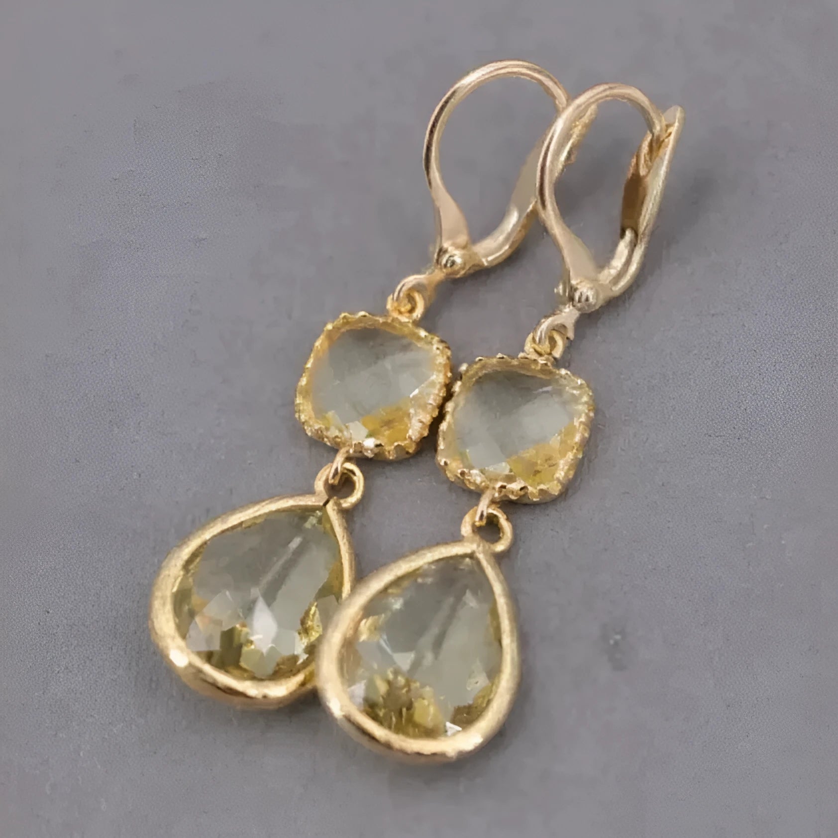 Gold long drop earrings with geometric shape and water droplet crystal fringe on a model.