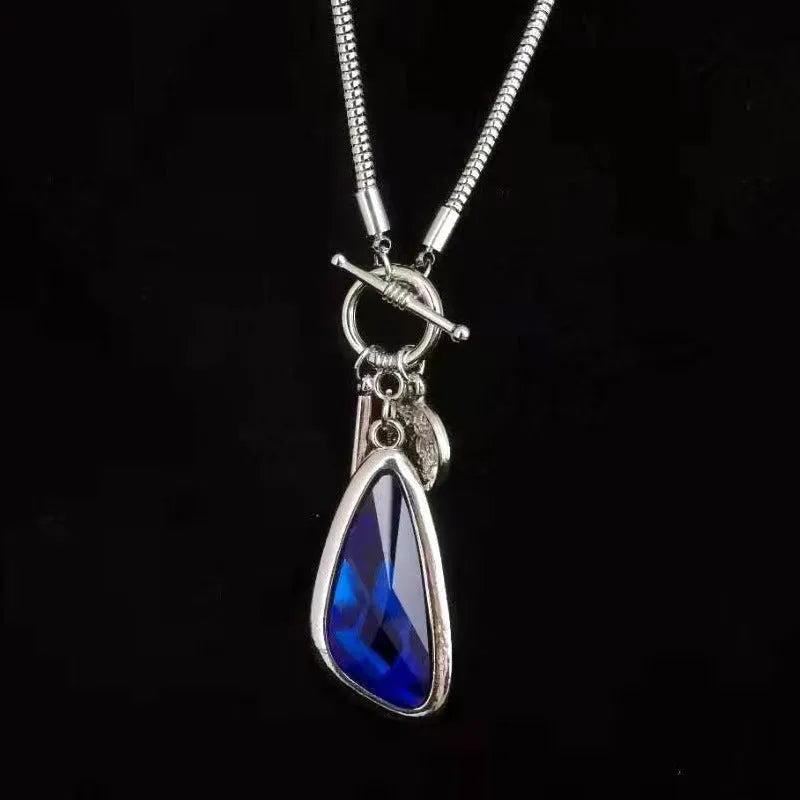 Long geometric alloy pendant necklace with snake bones chain for wearing over sweaters.