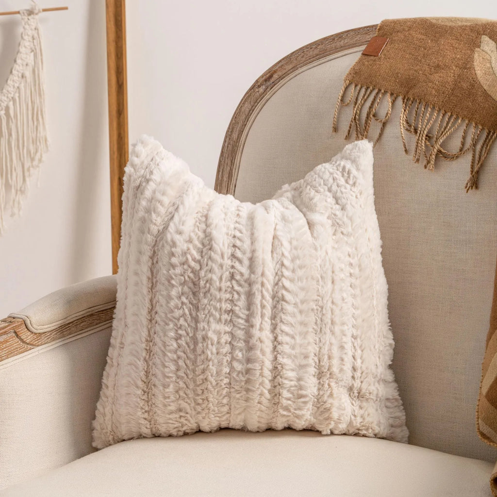 Knitted striped cushion cover with tassel trim in 45x45cm size on a sofa.