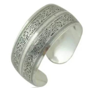 Ethnic style open carved Miao silver alloy bracelet in Roman shape on wrist.